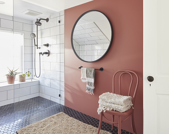 Baño con pared roja y un gran espejo colgante.