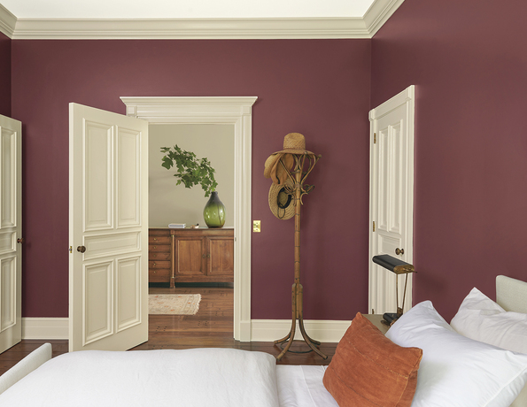 Red bedroom with white trim, coat rack with hats.