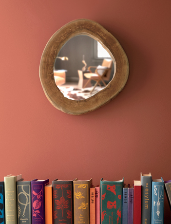 Biblioteca en color Rosy Peach con libros y pequeño espejo.