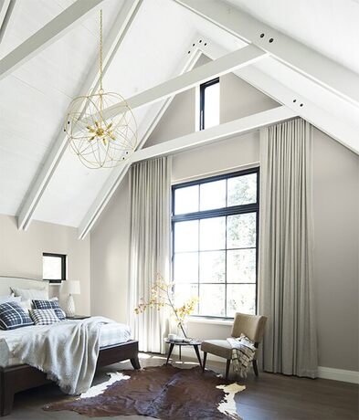 Dormitorio en el último piso con techos altos blancos y paletas de colores neutros