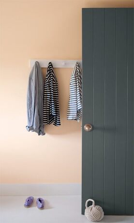 Una puerta pintada de gris carbón se destaca contra una pared color melocotón