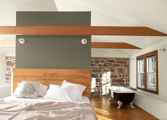 Dormitorio loft en blanco, pared decorativa en verde salvia, vigas de madera, pared de piedra