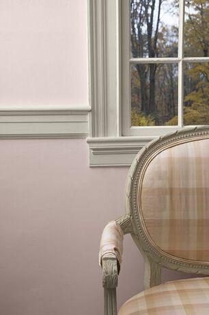 Paredes pintadas de rosa apagado con molduras de ventanas de color blanquecino y una silla a cuadros
