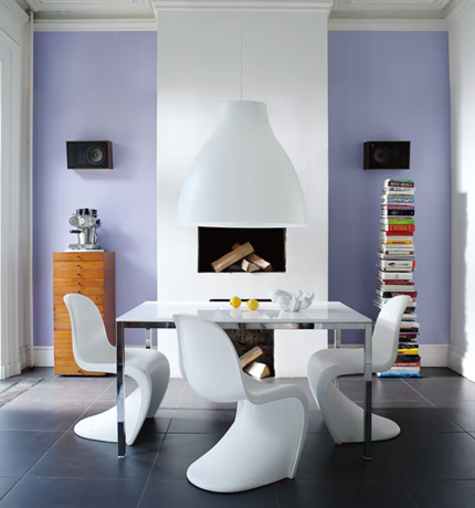 A modern home with lavender walls, featuring a fireplace, white dining table and chairs