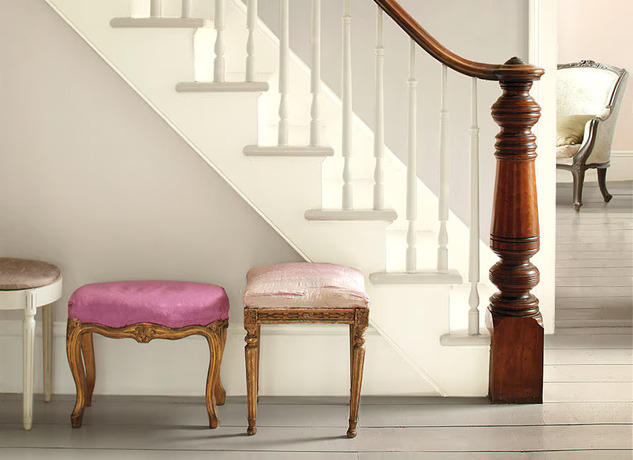 Gray walls accented by white stairs create an elegant entryway featuring three ornate stools.