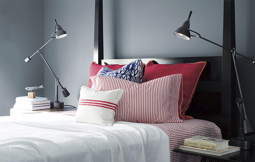 Sleek, Wolf Gray-painted bedroom with black bedframe, red and white bedding, two swing-arm lamps