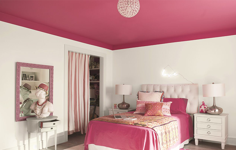 White bedroom walls with a bright pink ceiling and matching pink bedding with tables and lamps.