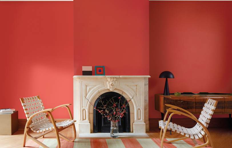 Sala de estar con paredes pintadas de color rojo Raspberry Blush, chimenea de mármol blanco.