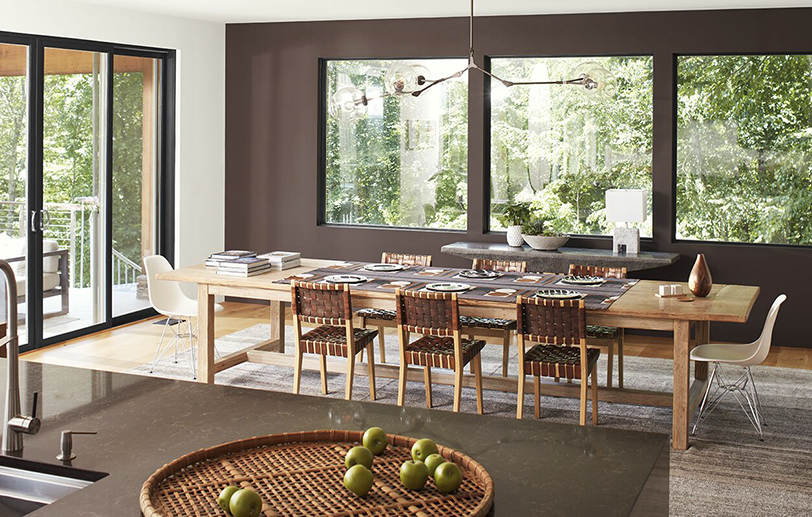 Modern dining room with brown accent wall, white ceiling & glass doors, and brown granite island.